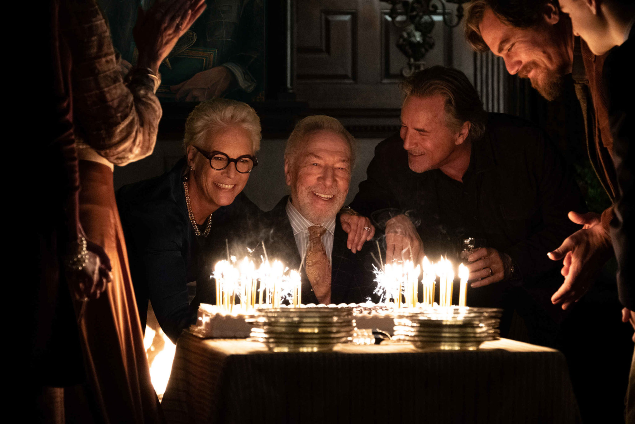 Family members gather around a cake with burning candles in Knives Out